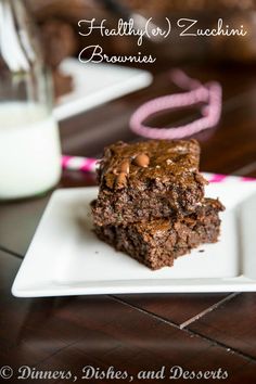 two brownies on a white plate with milk in the background