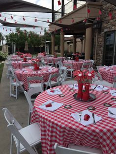 tables with red and white checkered tablecloths are set up in front of a building