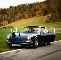 a blue sports car is parked on the side of the road in front of a golf course