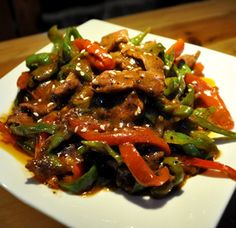 a white plate topped with meat and veggies on top of a wooden table