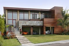 a large house with lots of windows and stairs leading up to the front yard area