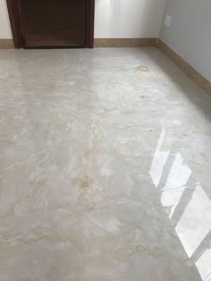 an empty room with marble flooring and door in the corner, looking into the hallway