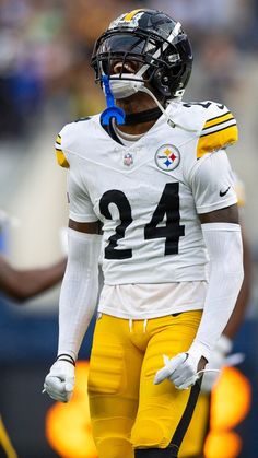 a football player wearing a helmet and holding a blue object in his mouth while standing on the field