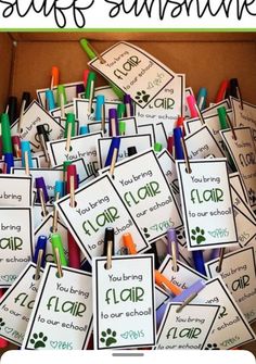 a box filled with lots of different colored crayons and name tags on clothes pins