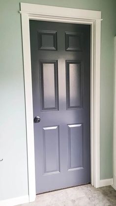 an empty room with a blue door and white trim on the walls, carpeted floor