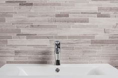 a white sink sitting under a faucet next to a wall mounted soap dispenser