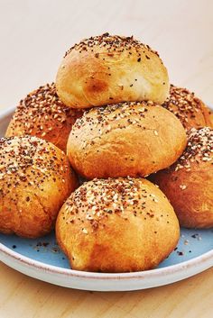 a blue plate topped with rolls covered in sesame seeds