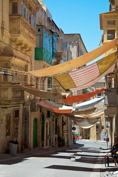 an empty city street with lots of flags hanging from the buildings and people sitting on benches