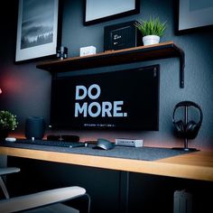 a computer desk with a monitor and headphones on it, next to a plant