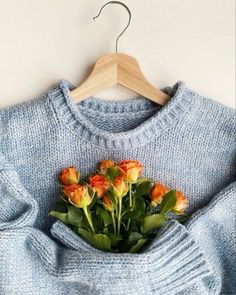 a blue sweater with flowers in the pocket