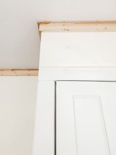 the corner of a room with white painted walls and wood trimming on the door