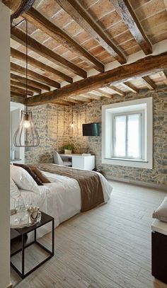 a bedroom with stone walls and wooden beams in the ceiling, along with a large bed