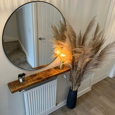 a mirror sitting on top of a wooden shelf next to a radiator and plant