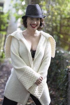 a woman wearing a white coat and black hat