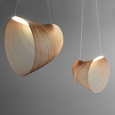 two wooden lamps hanging from strings in the shape of circles on a gray background,