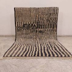 a black and white area rug on the floor in front of a wall with an animal print pattern