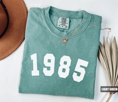 Product: Comfort Colors® 1985 Shirt, 39th Birthday Shirt, Personalized Shirt, Custom Birthday T-shirt, 39 Shirt, 1985 Birthday Shirt, Gift For Her ✦ MAKE IT PERFECT and Customize this shirt for FREE! Just shoot us a message BEFORE purchasing and we will work with you to create a design you'll love. ✦ SIZING CHART Please refer to the sizing chart in the pictures above to find your perfect fit! Simply lay your favorite T-shirt flat and measure armpit to armpit then compare it to the size chart ima 1985 Birthday, 1984 Birthday, 1984 Shirt, 40th Birthday Shirt, 40 Shirt, 39th Birthday, 40th Birthday Shirts, Custom Birthday, Birthday Shirt