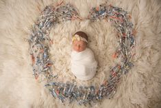 a baby wrapped in a white blanket laying on top of a pile of legos