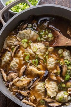 a pot filled with dumplings and vegetables on top of a wooden table