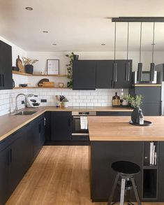 a kitchen with wooden floors and black cabinets is pictured in this image, there are stools on the counter