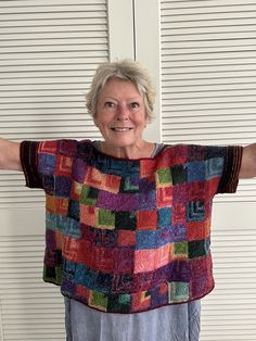 an older woman wearing a multicolored sweater with her arms outstretched in front of the camera