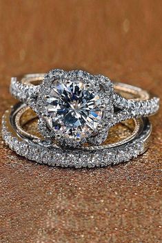 two wedding rings with a diamond center surrounded by diamonds