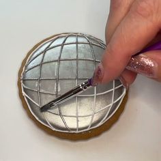 a person is using a pen to decorate a cookie with metallic foil on it's surface