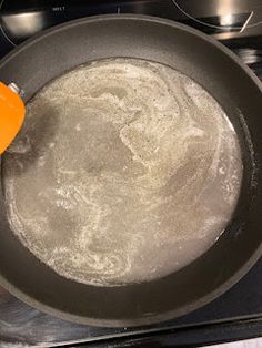 an orange spatula is being used to stir food in a pan on the stove