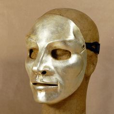 a gold mask with a black bow on it