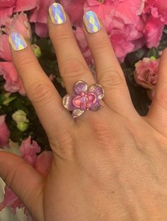 a woman's hand with pink flowers on it and a ring in the middle