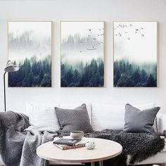 three paintings hang on the wall above a coffee table in a living room with two couches