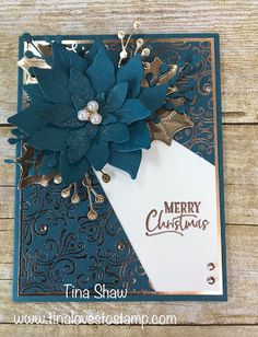 a christmas card with a blue flower on it and a white tag hanging from the front