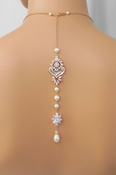 the back of a woman's neck wearing a necklace with pearls and diamonds on it