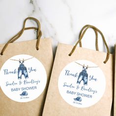 three brown paper bags with baby shower tags attached to them on a marble countertop