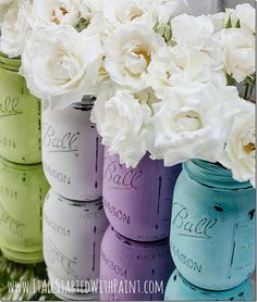 there are many painted mason jars with flowers in them