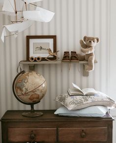 there is a teddy bear sitting on top of a dresser next to pillows and books