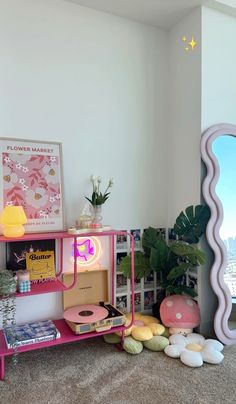 there is a pink shelf with various items on it and a mirror in the corner