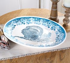 a blue and white plate sitting on top of a wooden table next to a candle