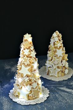 two small white christmas trees sitting on top of a blue table covered in frosting