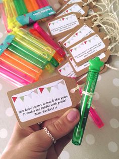 a hand holding a green pen next to some small tags with writing on them and paper clips