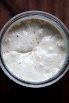 a glass filled with white liquid sitting on top of a wooden table next to a knife