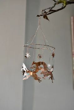 a mobile hanging from a tree branch with stars and deers on it's sides