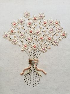 a tree made out of pearls and beads on a white surface with a pink bow hanging from it's center