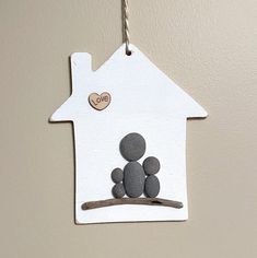 a paper house with two rocks in the shape of a family sitting on a tree branch