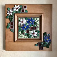 a wooden frame with flowers and leaves on the inside is decorated in green, white, and blue