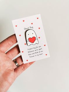 a hand holding a card with an image of a heart in it and the words ghost hug