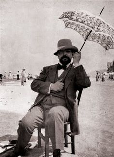 an old photo of a man sitting on a chair with an umbrella in his hand