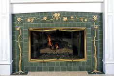 a fire place with a green brick fireplace and gold trimmings on the mantle