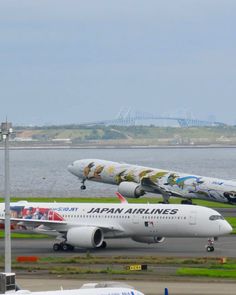 two airplanes are parked on the tarmac at an airport near some water and grass