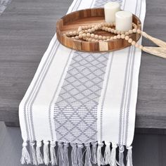 a wooden tray with candles and beads on it sitting on a table next to a candle holder